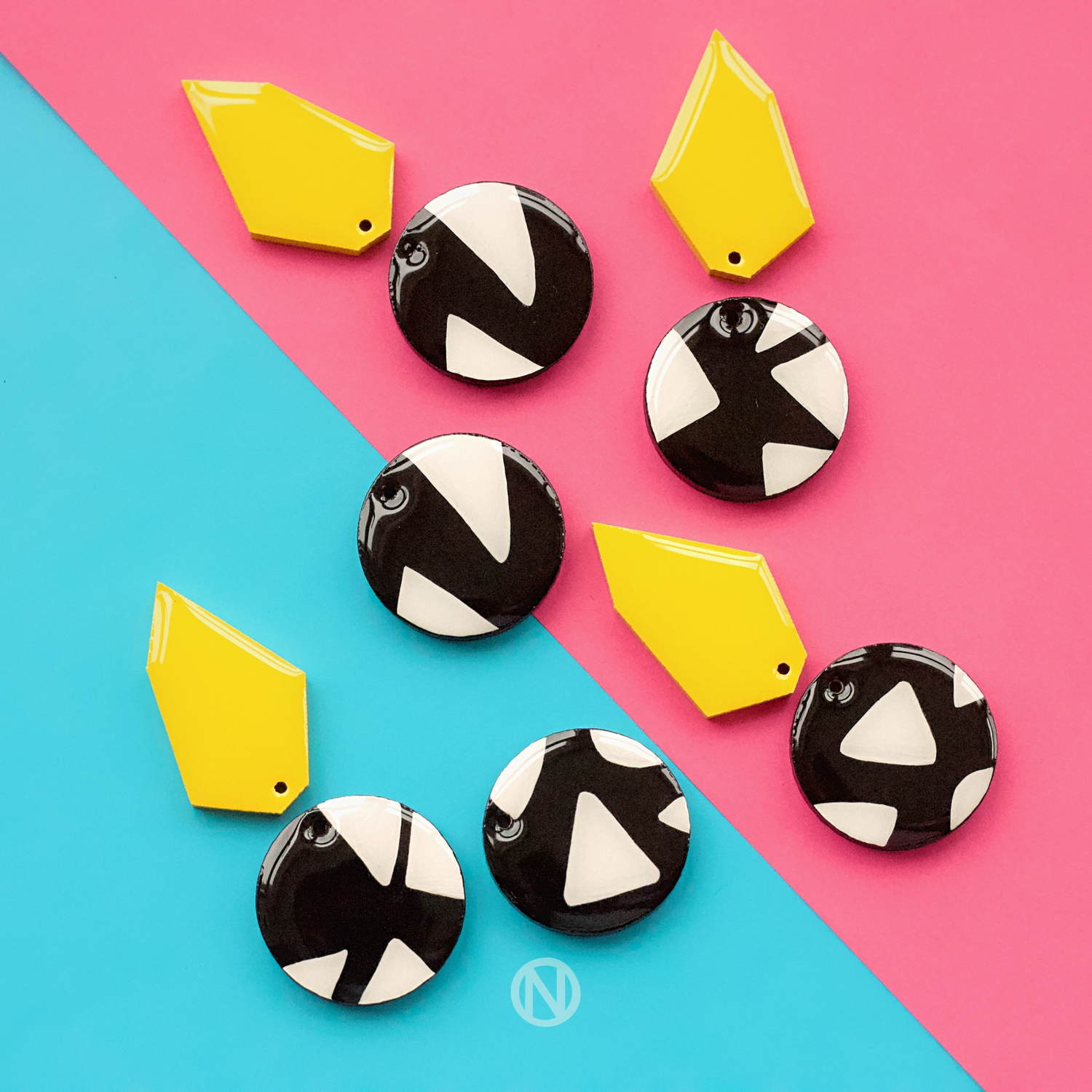 Earrings with a yellow geometric shape on top, and a black and white circle section at the bottom with a triangle pattern.