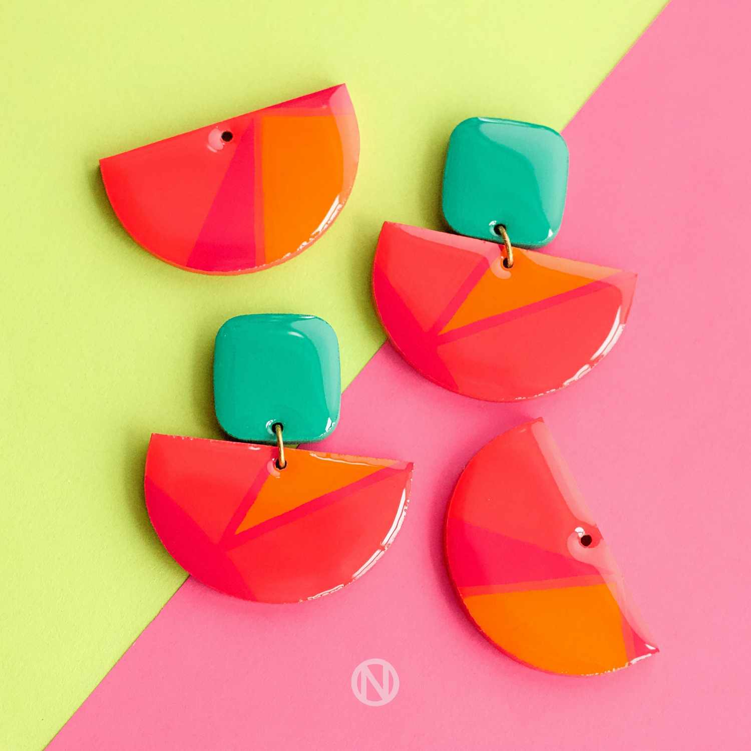 Earrings with a turquoise rounded rectangle shape on top, and a pink and orange semi circle section on the bottom.